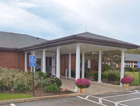 Exterior view of Greensburg Care Center entrance with covered walkway and planters.