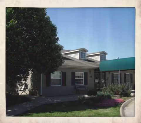 Front view of a single-story assisted living building with green awning and landscaping.