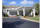 Front view of NHC Place Anniston facility with white porte-cochère and landscaped entrance.