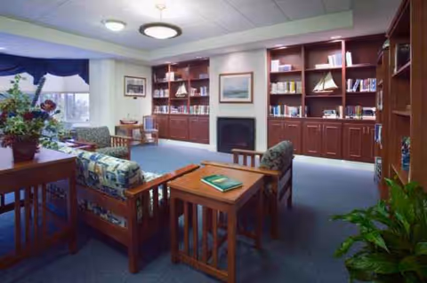 Cozy senior living library lounge with couches, bookshelves, and a fireplace.