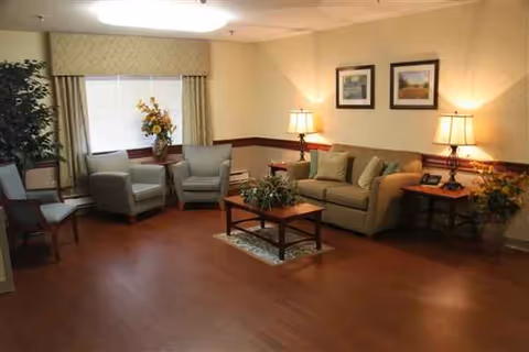 Cozy lounge in a senior facility with sofas, chairs, lamps, and plants.