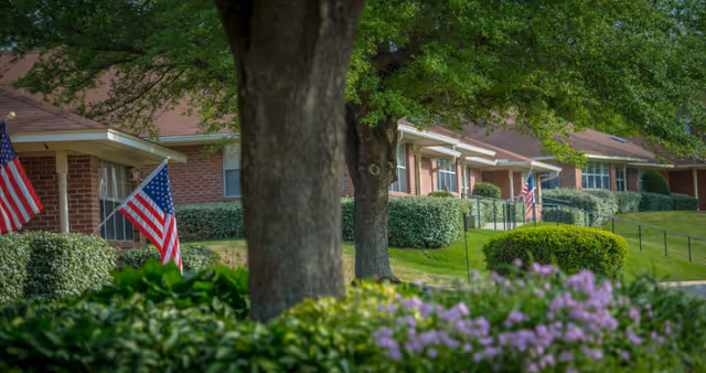 Exterior view of Parkway Village senior living facility with brick buildings, flags, and landscaping.