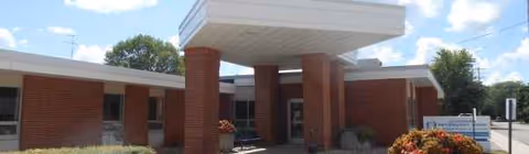 Brick, single-story retirement facility with a covered entrance and landscaped front area.