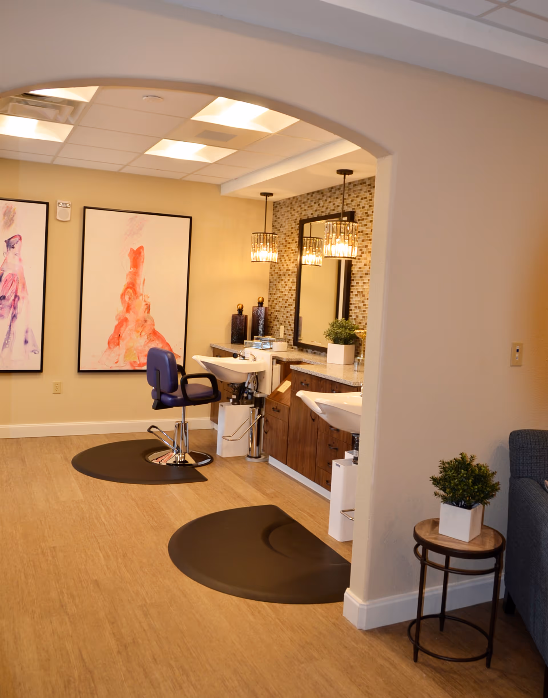 Interior salon area with hair-washing stations, salon chairs, mirrors, pendant lights and wall artwork.