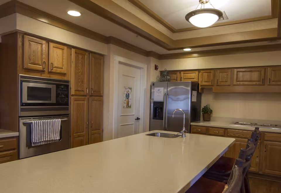 Spacious kitchen with a large island and sink, wooden cabinets, and stainless steel appliances.