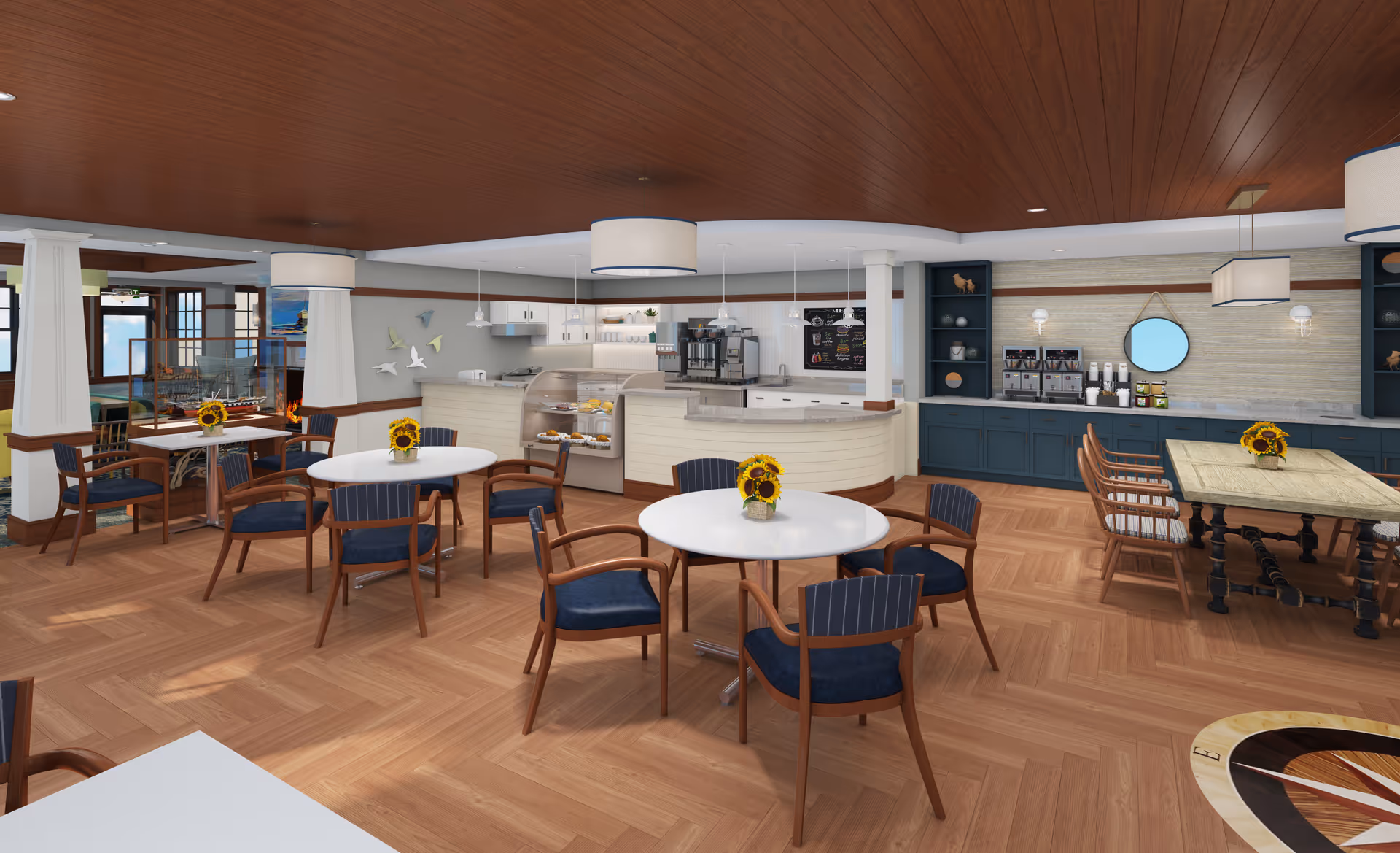 Bright dining area with round and rectangular tables, blue-upholstered chairs, sunflowers on tables, and a central service counter and coffee station.
