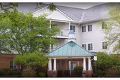 Front entrance of Meadows At Salem Run Senior Apartments with a porte-cochere and greenery.