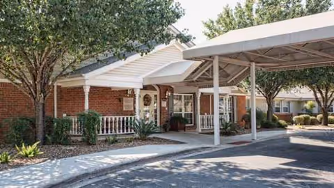 Exterior view of Arden Courts memory care entrance with brick facade and covered walkway.