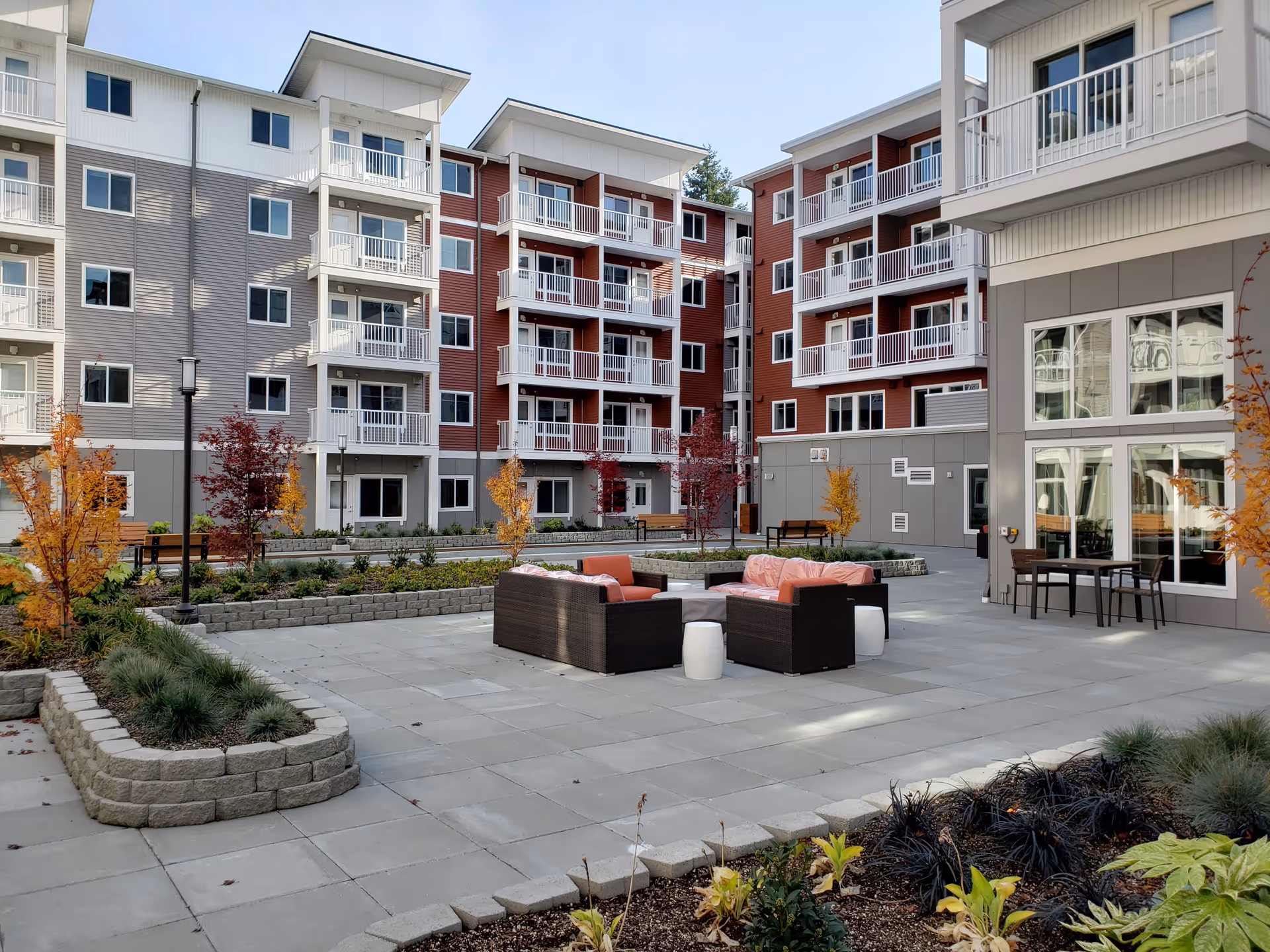 Courtyard patio with outdoor seating, planters, and small trees surrounded by a multi-story residential building with balconies.