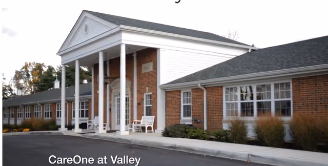 Exterior view of Harmony Village at CareOne Valley featuring brick building and white columns.