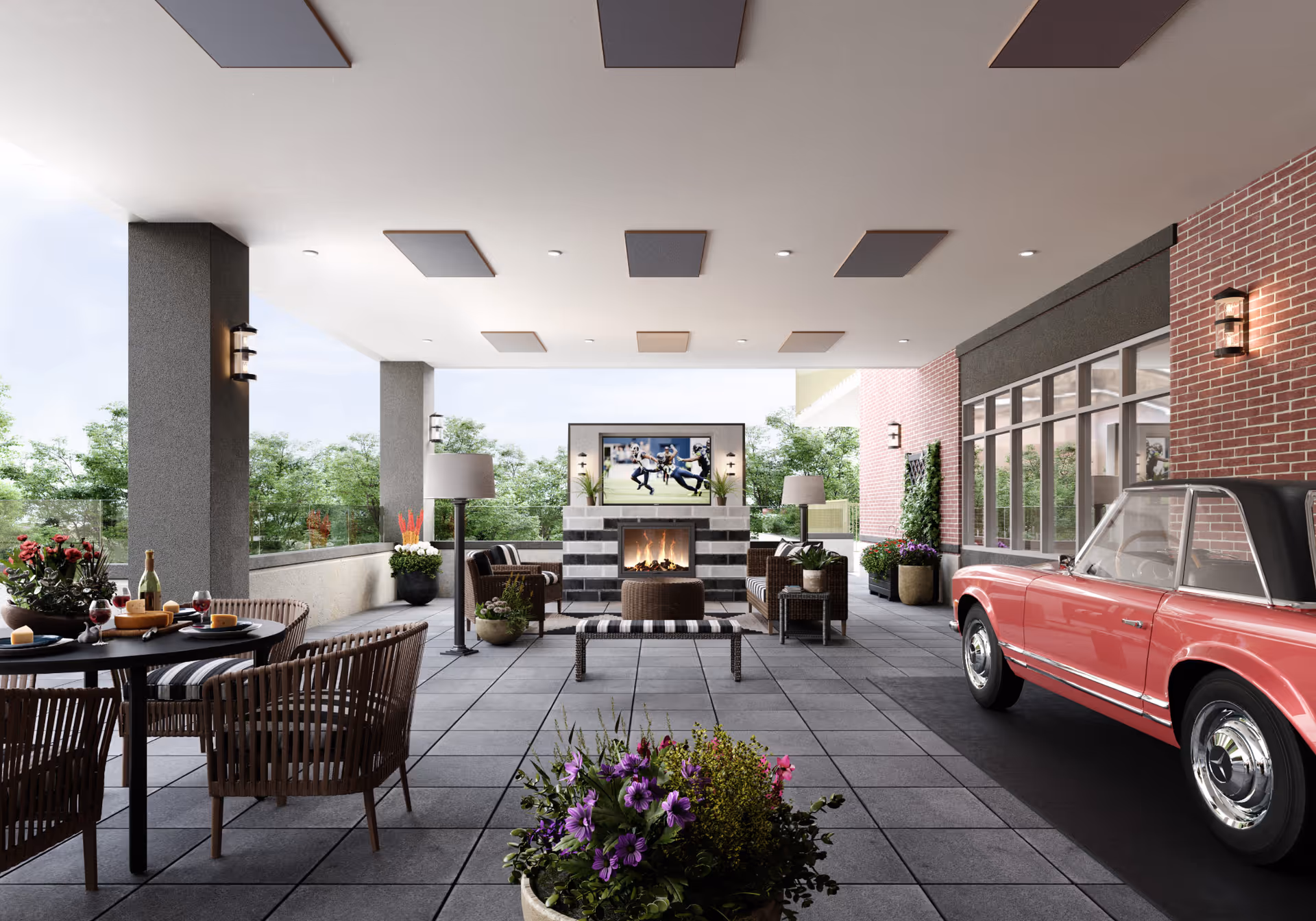 Covered outdoor patio at a senior living community with seating around a fireplace and TV, dining table, potted plants, and a red classic car at the entrance.