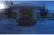 Snow-covered front entrance of Pioneer Place Assisted Living under a curved canopy.
