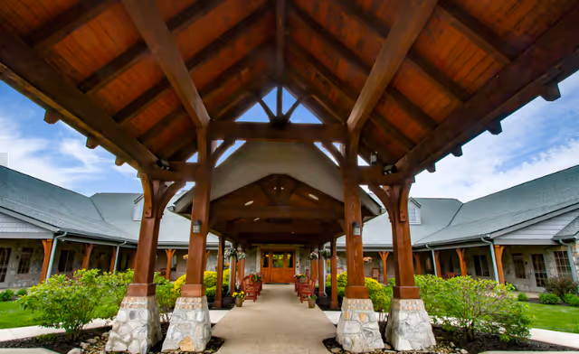 A covered wooden entrance walkway with stone pillars leading to the building front.