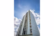 Tall modern apartment building seen from below against a blue sky with clouds.