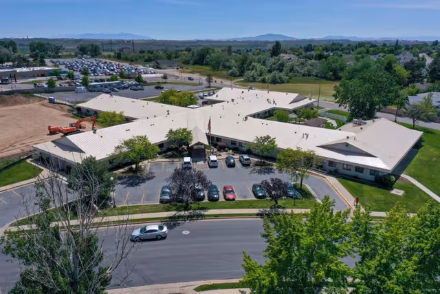 Aerial view of Mt. Ogden Health And Rehabilitation Center, a single-story X-shaped building with a front parking lot, flagpole, and surrounding trees and lawns.
