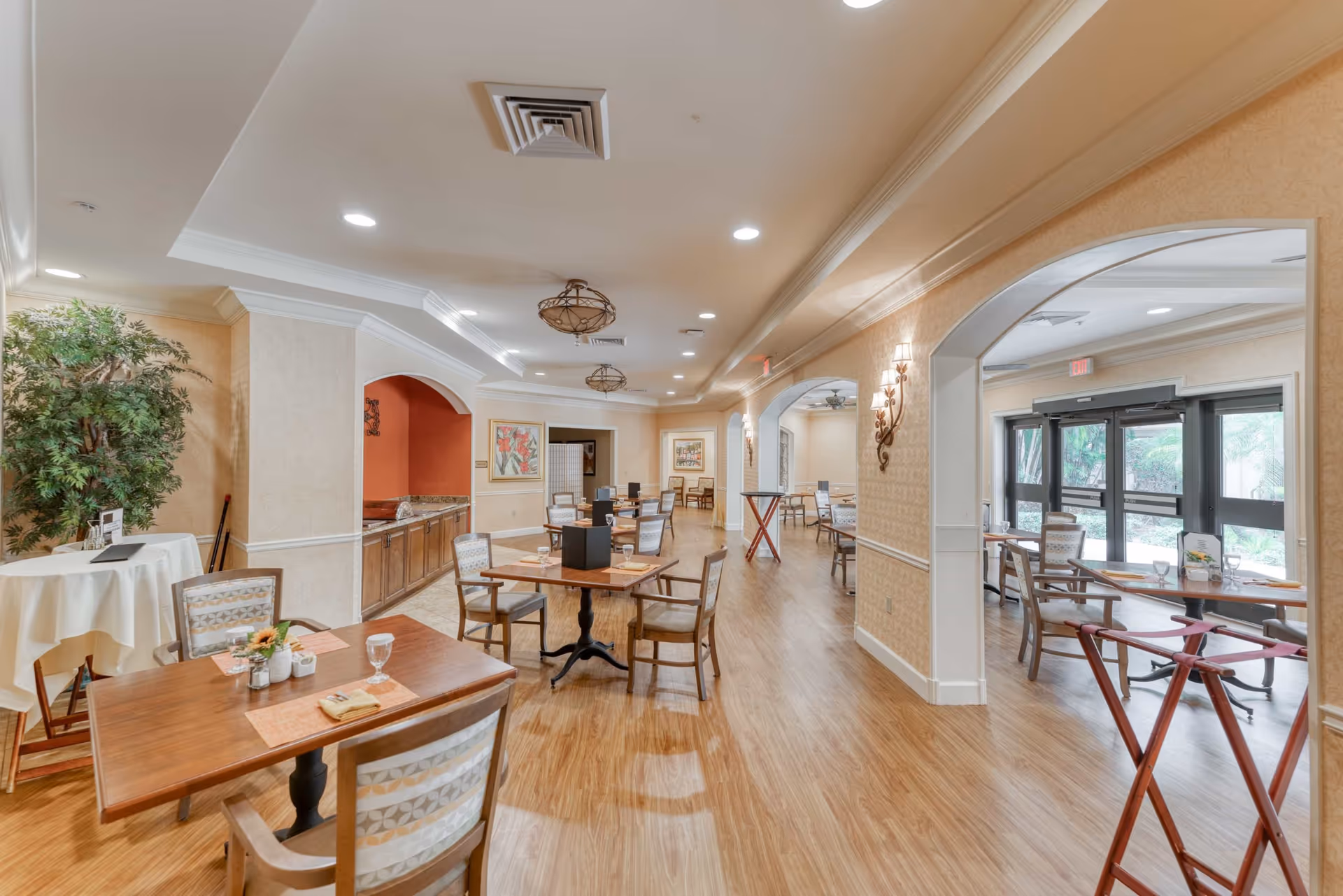 Spacious, well-lit communal dining area with multiple tables and chairs, wood floors, and large windows.