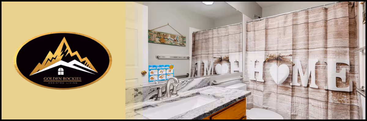 Bathroom vanity with sink and mirror next to a shower curtain printed with the word 'HOME' and a heart, beside a Golden Rockies Assisted Living logo.