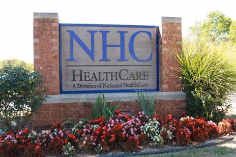 NHC HealthCare sign on brick pillars with blooming flowers in a landscaped front yard