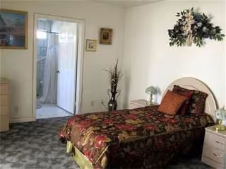 A small bedroom with a floral quilt, nightstands, and a doorway to a bathroom.