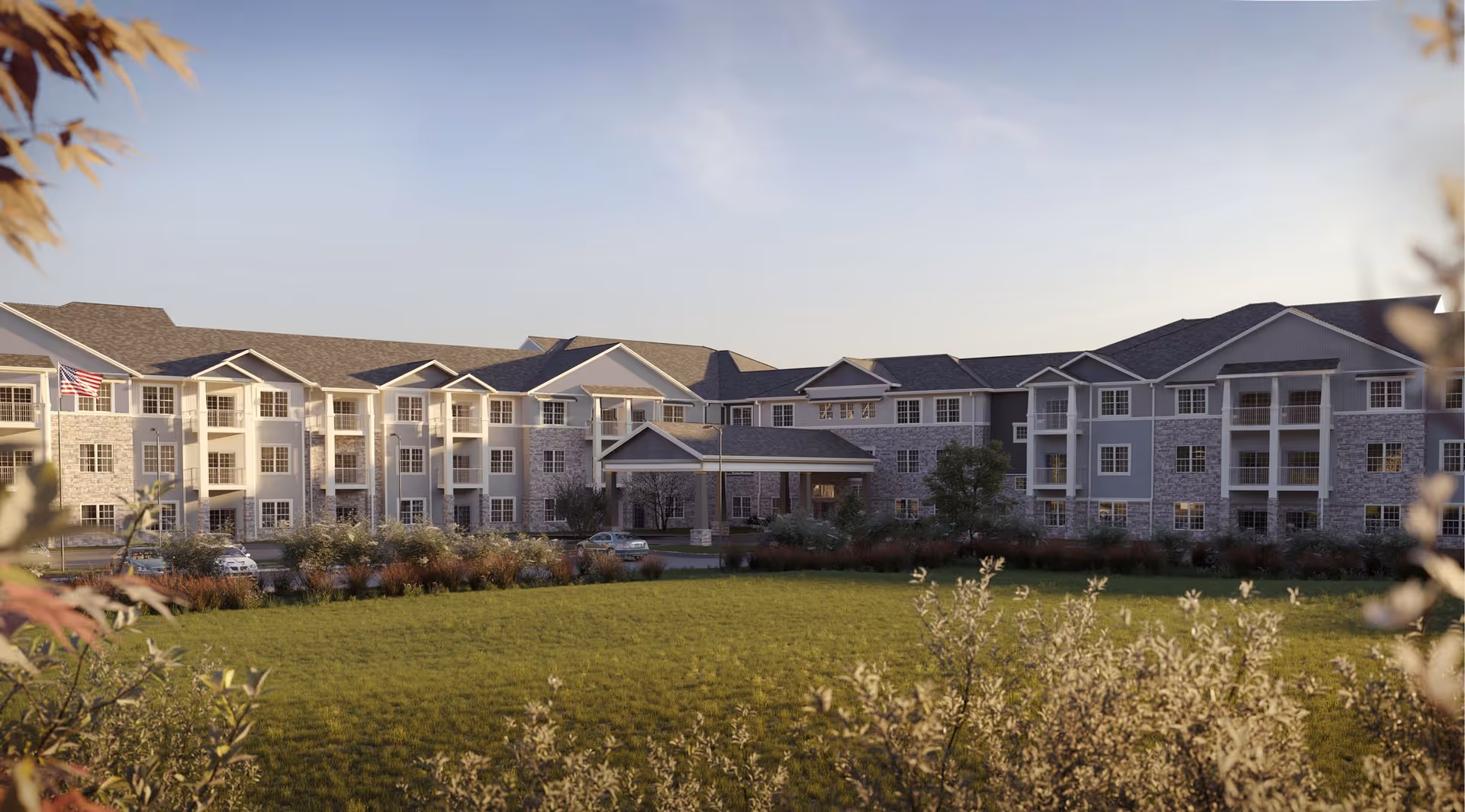Exterior view of a multi-wing senior living building with a central entrance and green lawn.