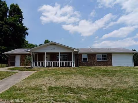 A single-story brick senior living facility with a front porch and lawn.