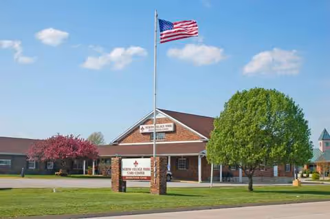 Exterior view of North Village Park facility with flag, trees, and front entrance.