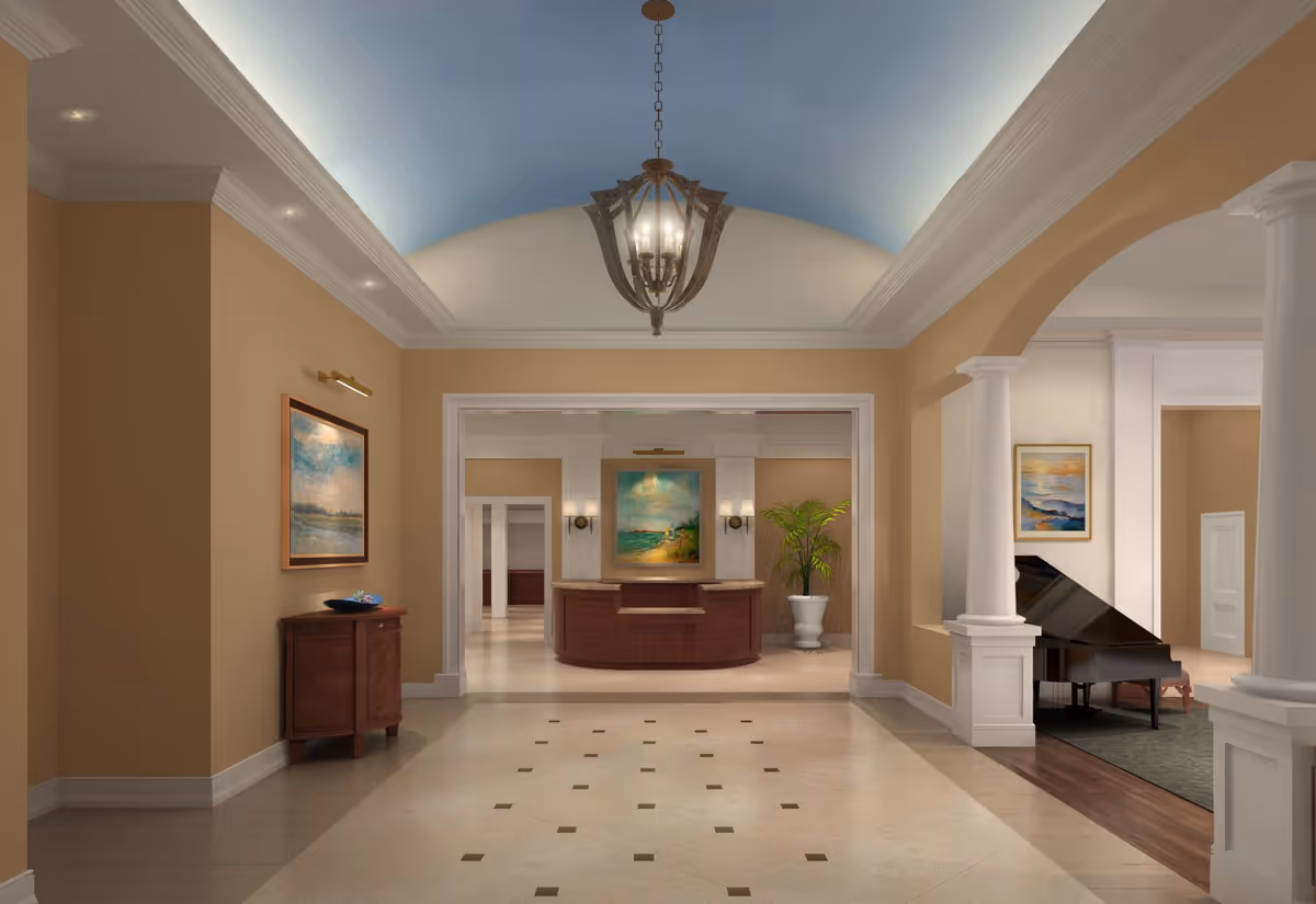Spacious and elegant interior hallway of a senior living facility with beige walls, a light blue vaulted ceiling, a chandelier, and polished tile flooring. The hallway leads to a reception desk with a painting and potted plant behind it. To the right, there is a grand piano in a room with white columns and framed artwork on the walls.