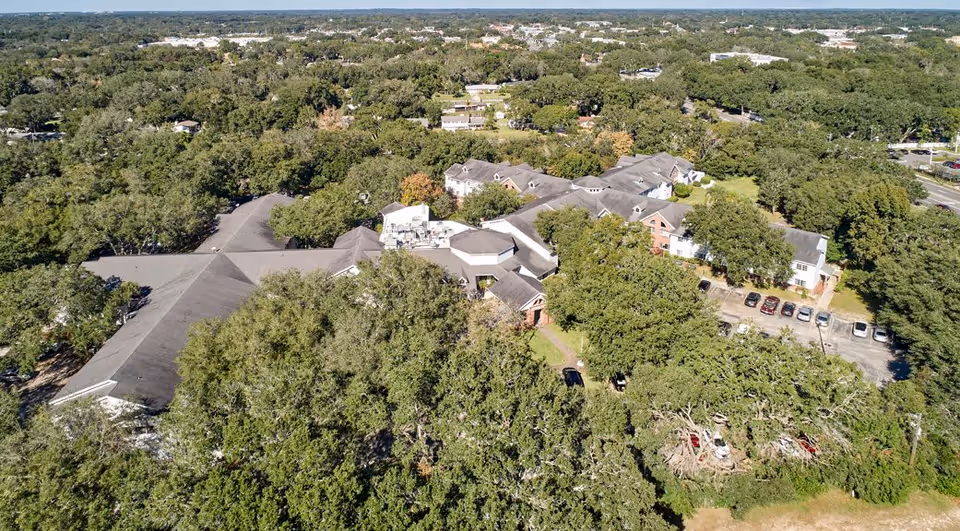 Aerial view of a senior living facility complex with multiple connected buildings, surrounding trees, and parking areas.