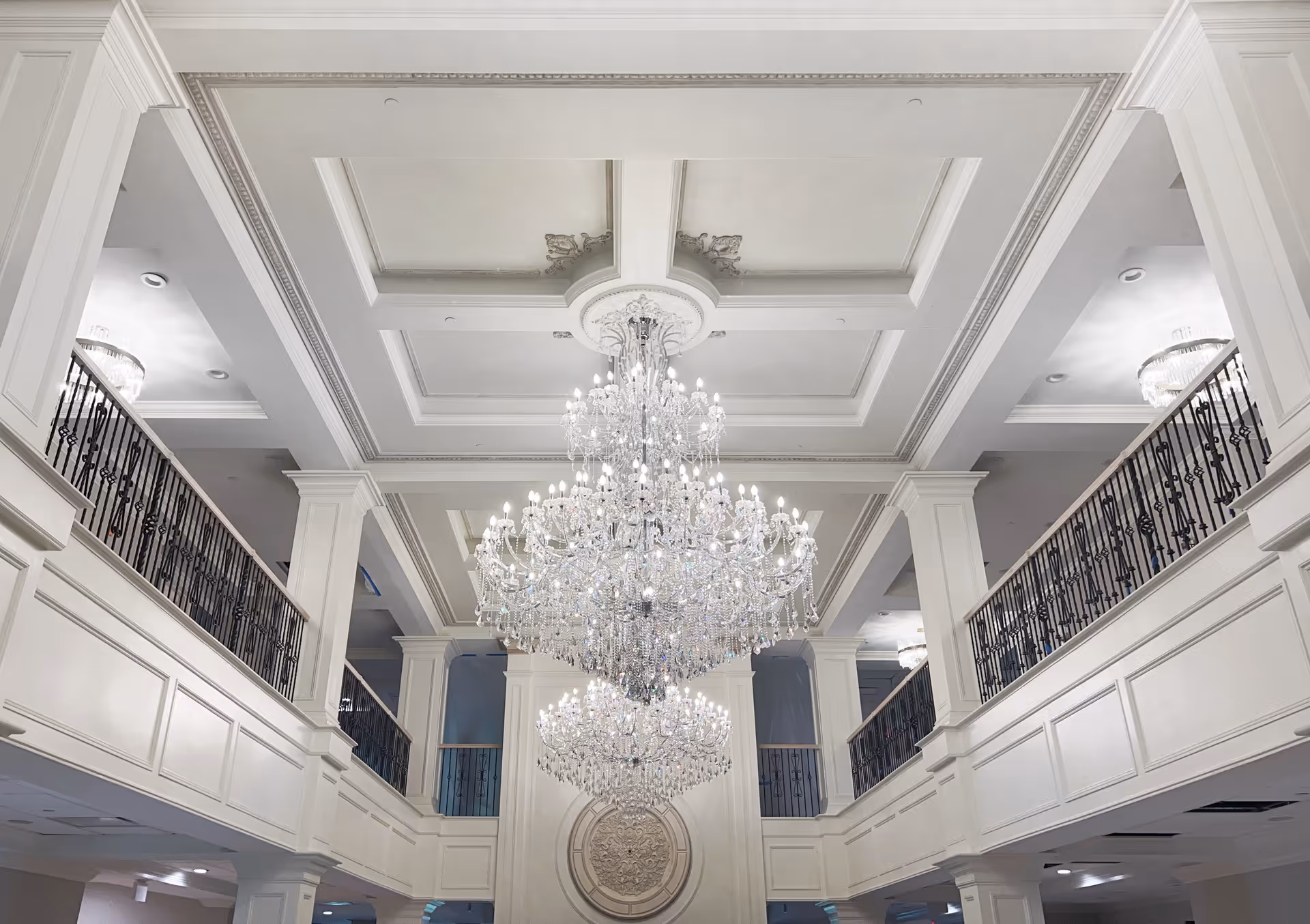 Ornate two-story interior lobby with large crystal chandeliers and second-floor balconies.