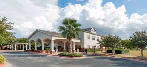 Exterior view of Parmer Woods at North Austin facility with driveway, palm trees, and entrance.