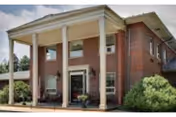 Brick senior living building with a covered entrance supported by columns.
