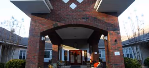 Brick entrance archway leads into a senior living facility with a covered walkway.