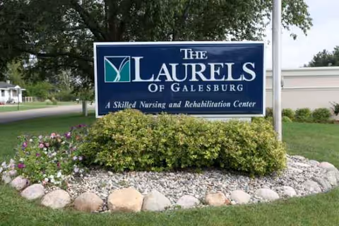 Front view of The Laurels of Galesburg sign with landscaped rocks and greenery.