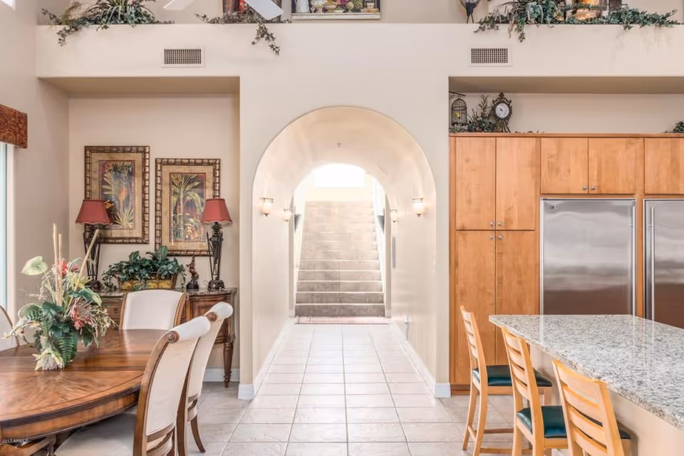 Bright dining area and kitchen with a central arched hallway leading to a stairway.