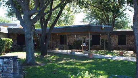 Exterior view of a single-story brick care center with a covered entrance and trees.