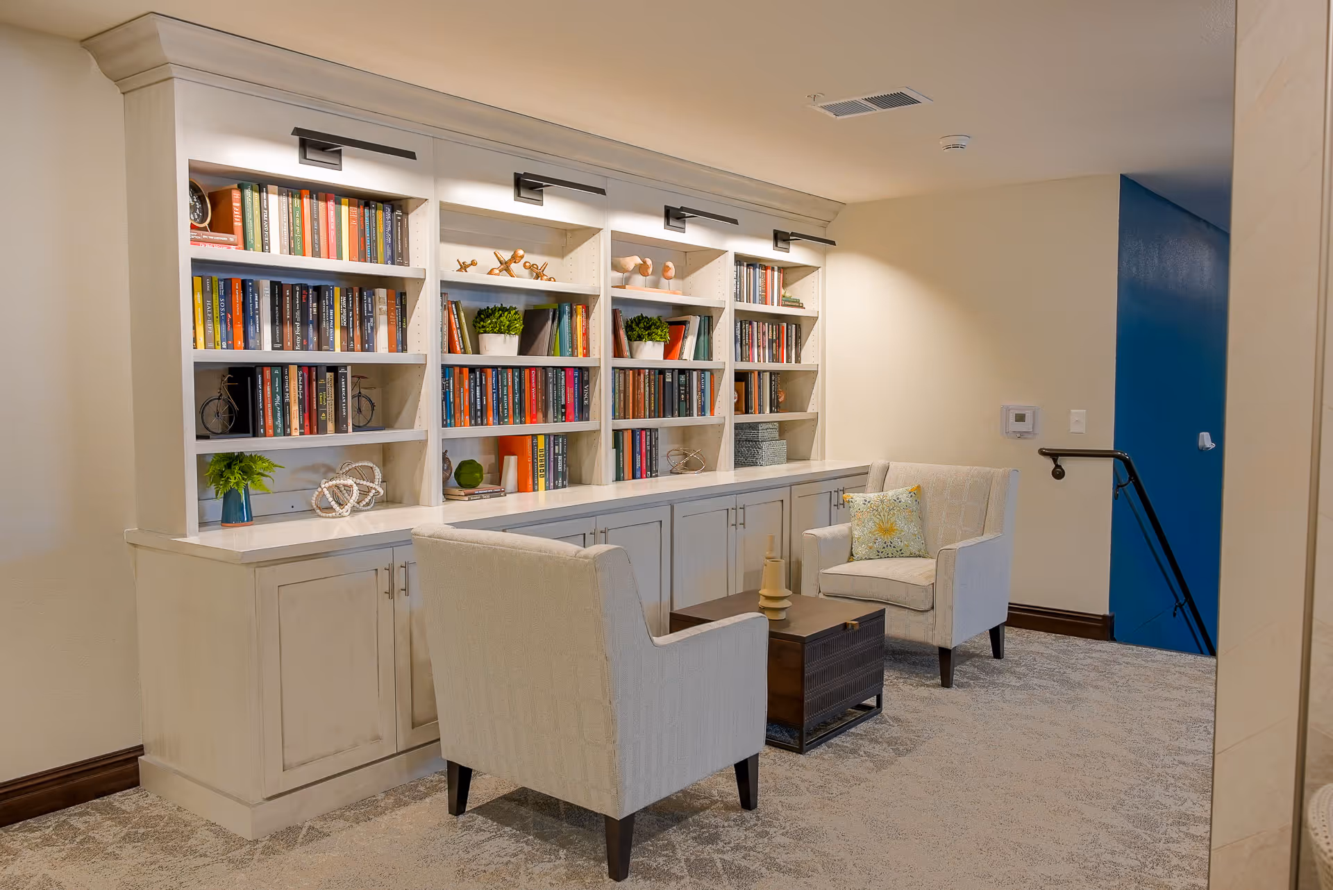 Cozy reading nook with built-in bookshelves, two upholstered armchairs, and a small coffee table.