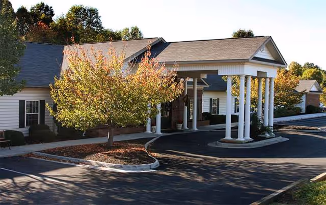 Exterior view of Eden Pines facility with trees, driveway, and covered entrance.
