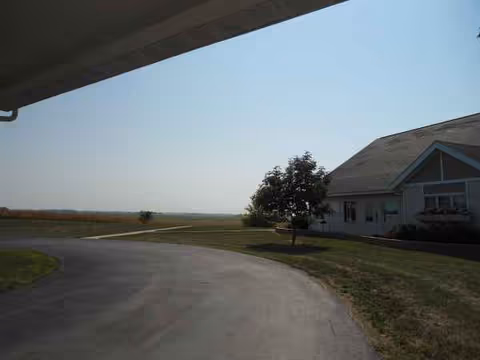 Exterior view of Hubbard Care Center with curved driveway, lawn, and tree