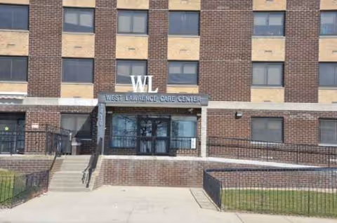 Front exterior of West Lawrence Care Center building with entrance and sign.