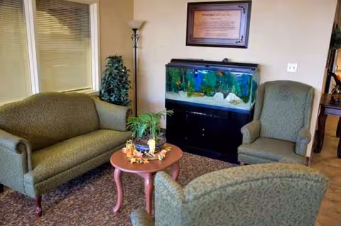Cozy indoor living room in a senior facility with sofas, chairs, and an aquarium.