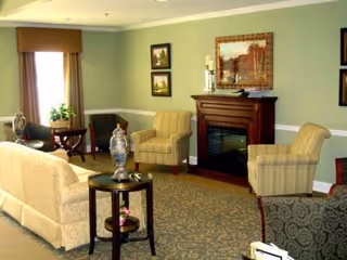 Cozy living room with sofas and armchairs arranged around a fireplace and side tables.