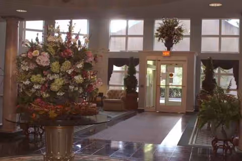 Senior living lobby with large floral arrangement, glass doors, and seating.