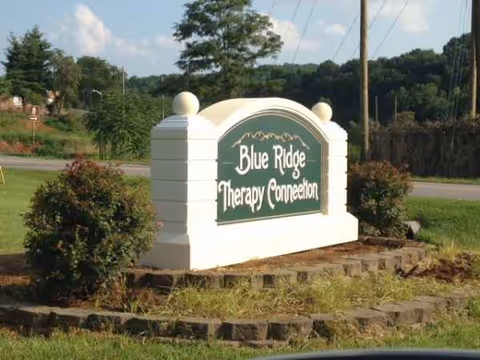 White roadside sign reading Blue Ridge Therapy Connection with green plaque and landscaped area