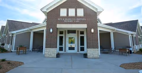 Front view of a brick senior living facility entrance with covered porches.