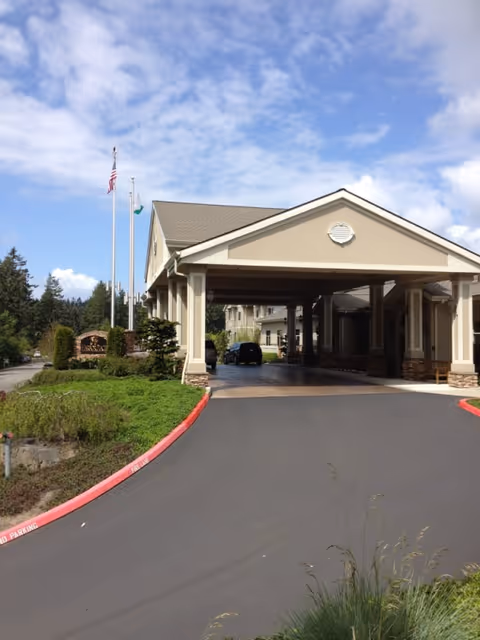 Front view of a senior living facility with a covered entrance and driveway.
