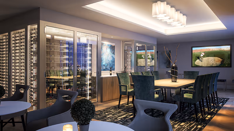 Modern dining area featuring a long wooden table with green upholstered chairs, glass-enclosed wine storage, and ambient ceiling lighting.