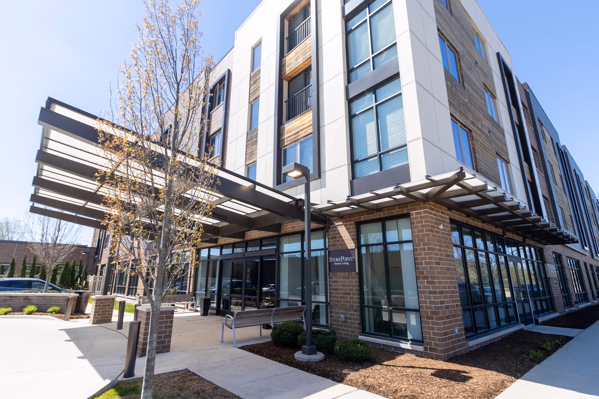 StoryPoint Birmingham exterior: modern, multi-story senior living entrance with glass walls and a covered walkway.