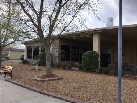 Exterior view of a single-story building with a covered entrance and landscaped front yard.