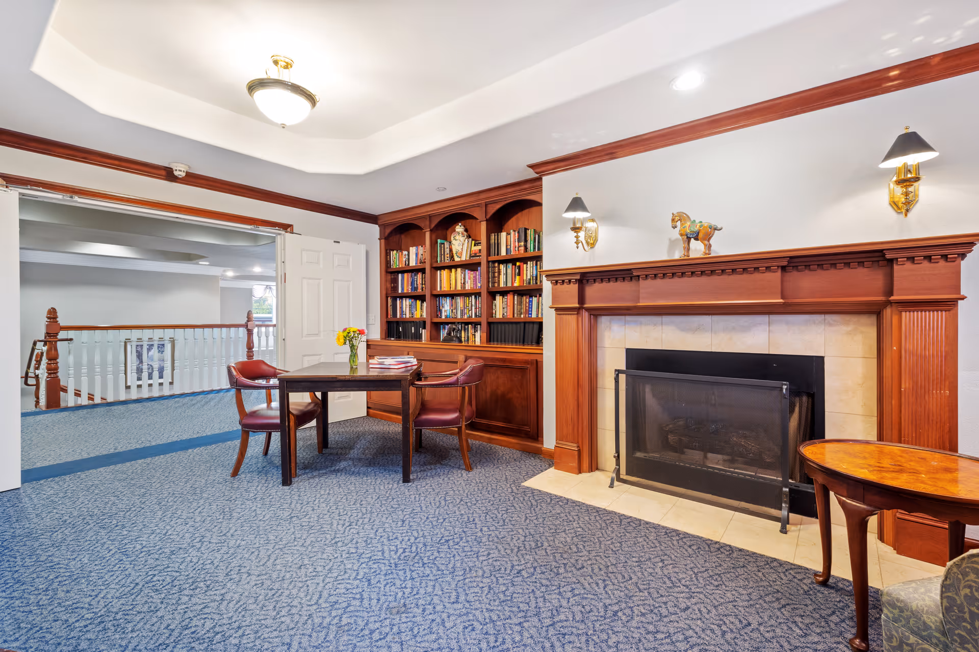 Cozy communal sitting area with a fireplace, built-in bookshelves, and a table with chairs.