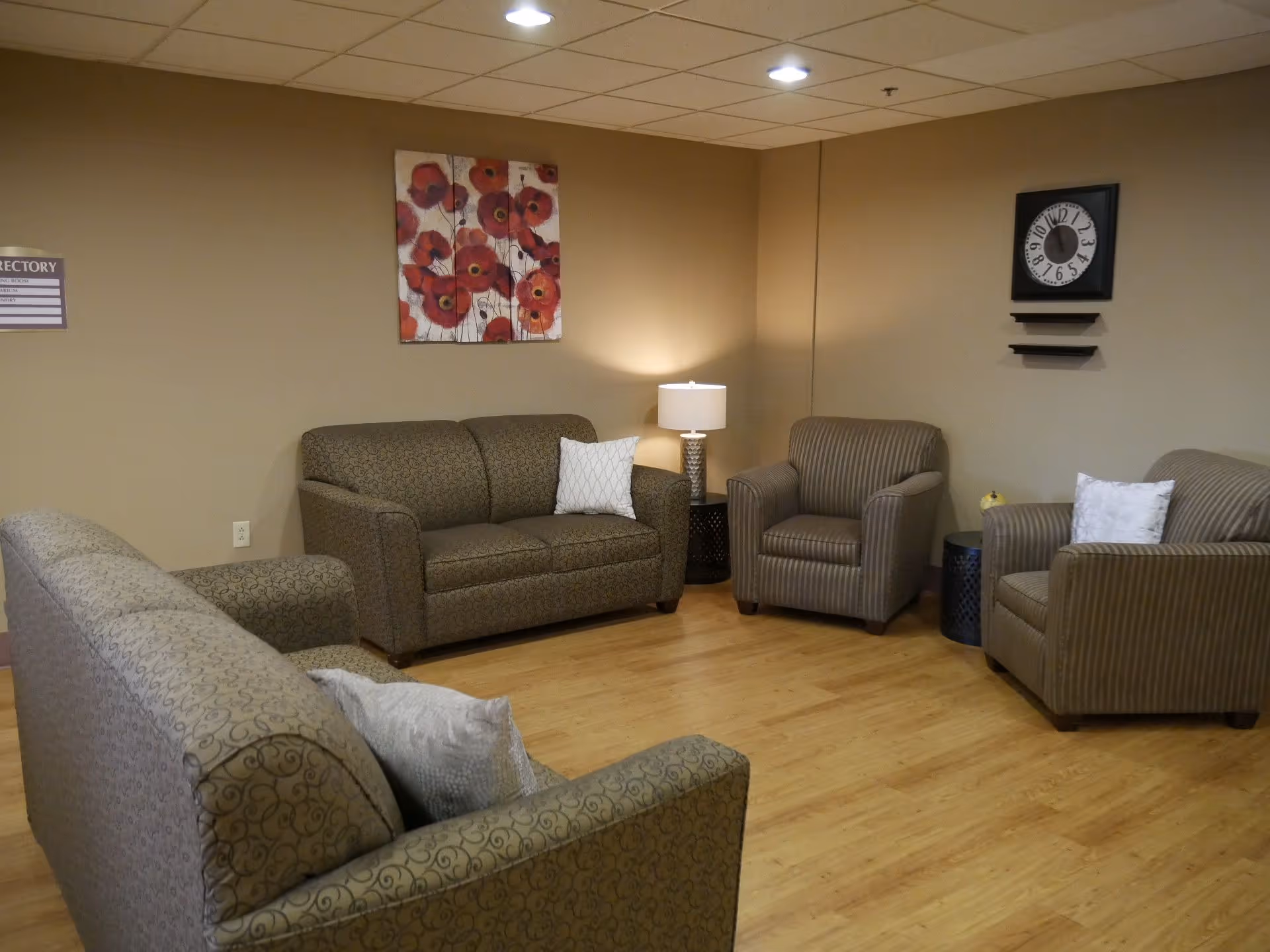 A comfortable seating area with sofas and armchairs, a lamp, and wall decor in a communal room.